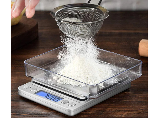 Sifting flour into a digital kitchen scale on a wooden surface