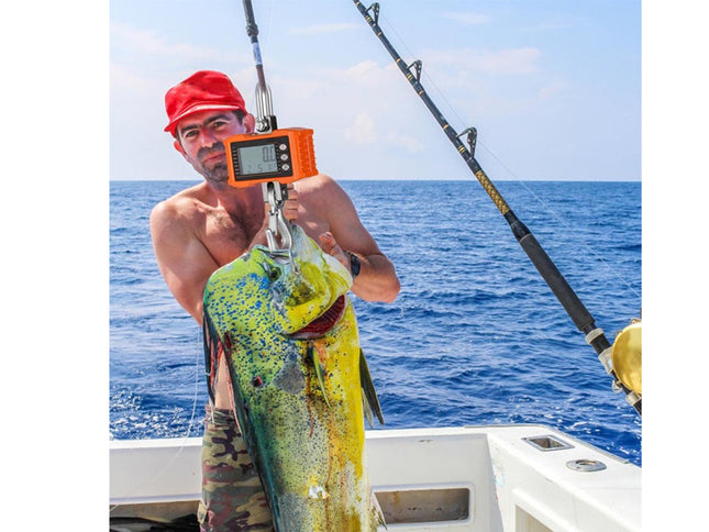 Man holding a large fish caught on a boat with ocean in the background