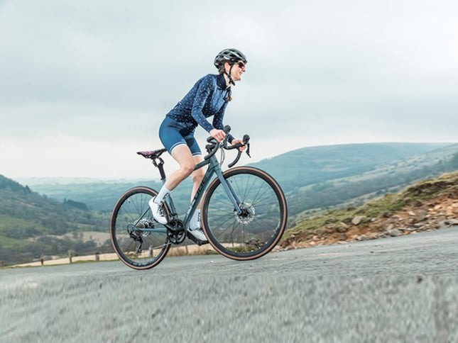 Person riding a bicycle on a road with a scenic background