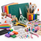 An assortment of arts, crafts, and DIY supplies, including colored paper, a cutting mat, scissors, a hot glue gun, paints, markers, beads, ribbons, and a rotary cutter on a white background.