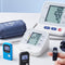 Blood pressure monitor with digital display and cuffs on a light surface.
