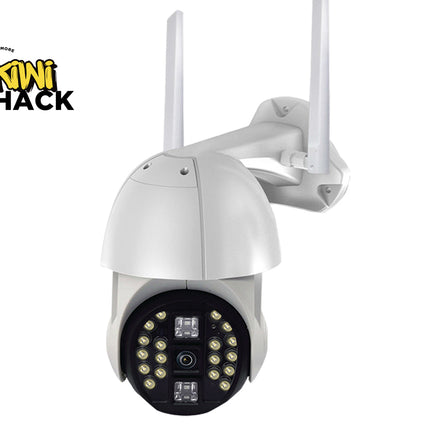 A white outdoor security camera with two antennas, a black circular faceplate containing multiple LED light elements, and a wall mounting bracket, shown on a white background with a Kiwi Shack logo in the top-left corner.