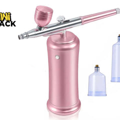 A pink and silver airbrush pen tool with a matching pink cap, shown on a white background with two translucent blue plastic cups. The Kini Shack logo is visible in the top-left corner.