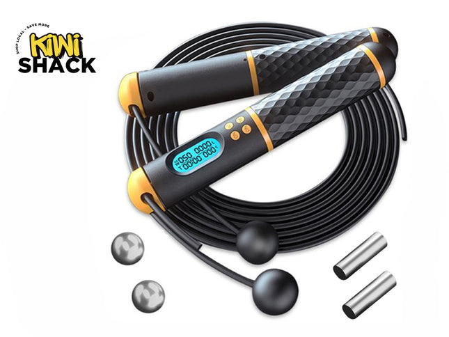 A black and yellow digital jump rope with textured handles, an integrated LCD screen showing workout data, a coiled black skipping rope, two optional short cordless weighted balls, and two metal weight inserts, set against a plain background with the "Kiwi Shack" logo in the top left corner.