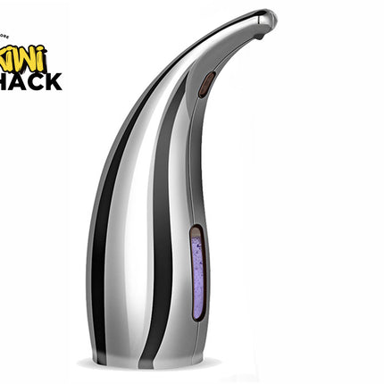 A polished silver automatic touchless soap dispenser with a curved nozzle and a vertical liquid level window showing purple soap inside, set against a white background. A "Kiwi Shack" logo appears in the top-left corner.