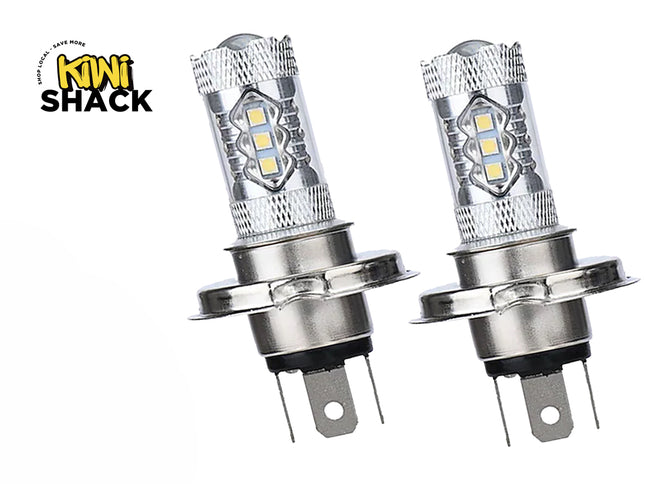 A pair of H4 LED headlight bulbs featuring silver metal housings, surface-mounted LED chips along the upper shaft, mounting collars, and bottom electrical connector pins against a white background, featuring the "Kiwi Shack" logo in the upper left corner.