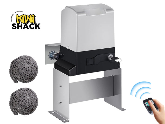 Silver and black automatic sliding gate motor / opener unit mounted on a stainless steel mounting bracket/stand, featuring a side drive sprocket, manual release key lock with inserted key, two coils of heavy roller drive chain lying to the left, a handheld wireless remote control being held/operated by a hand in the bottom right corner with blue signal waves, and the Kiwi Shack logo watermark.