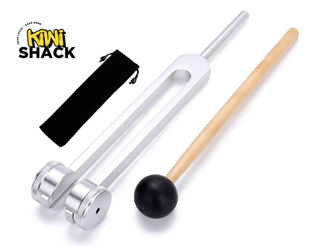 A large silver weighted tuning fork with screw-on weights, a wooden mallet with a black rubber ball head, and a black velvet storage pouch on a white background. A "Kiwi Shack" logo appears in the top-left corner.