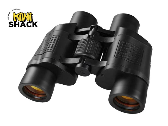 A pair of black binoculars with coated amber lenses and a central focus wheel, featuring the "Kiwi Shack" logo in the top-left corner.