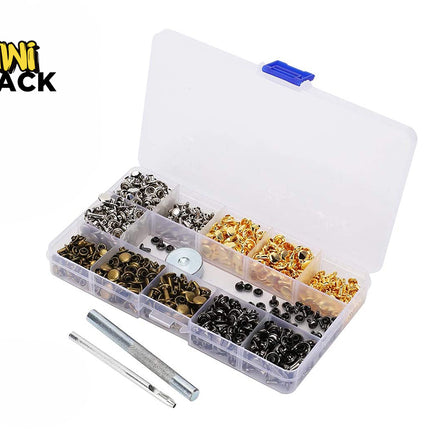 A clear plastic organizer box filled with assorted metal eyelets and rivets in black, silver, and gold finishes, shown open on a white background. Two small metal tools are placed in front.