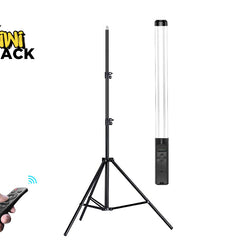A black tripod light stand with a tall cylindrical lamp attached, shown on a white background. A hand holding a black remote control appears in the lower left, and the Kiwi Shack logo is in the upper left.