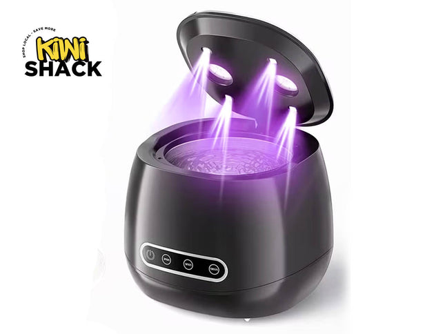 Black ultrasonic jewelry/lens cleaner machine with open lid showing purple ultraviolet disinfecting lights beaming down into a vibrating water basin, front control panel with timer buttons, and Kiwi Shack logo in top left.