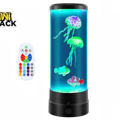 A cylindrical LED mood lamp filled with blue water containing floating artificial jellyfish and clownfish, accompanied by a white color-changing remote control on the left, set against a plain background with the "Kiwi Shack" logo in the top left corner.