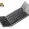 A compact gray tri-fold wireless Bluetooth keyboard with black keys and an integrated touchpad on the right section, featuring a "Kiwi Shack" logo in the top left corner.