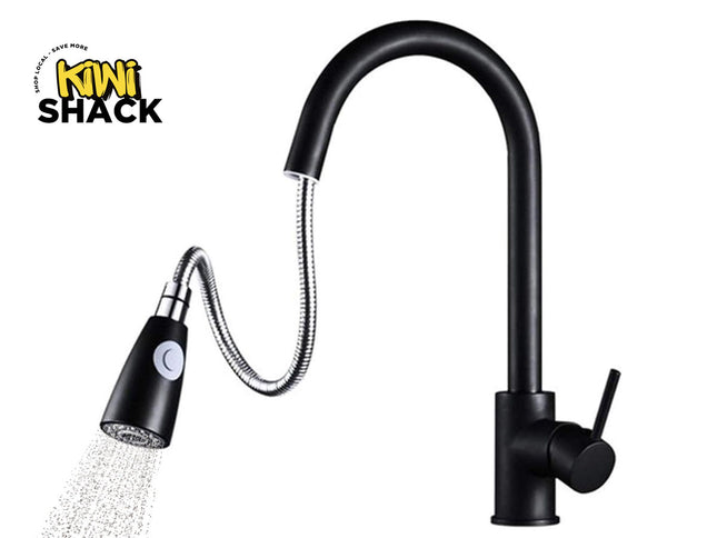 Matte black modern kitchen faucet with a high-arch rigid upper spout, flexible stainless steel pull-down gooseneck hose section, black and chrome spray head spraying water, single-lever side handle, cylindrical vertical body, and the Kiwi Shack logo watermark.