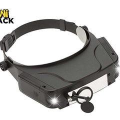A black magnifying headlamp with an adjustable headband, front light panel, and side adjustment knobs, shown on a white background with a Kiwi Shack logo in the top-left corner.