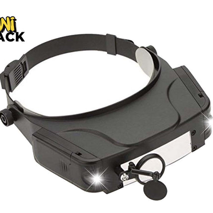 A black magnifying headlamp with an adjustable headband, front light panel, and side adjustment knobs, shown on a white background with a Kiwi Shack logo in the top-left corner.