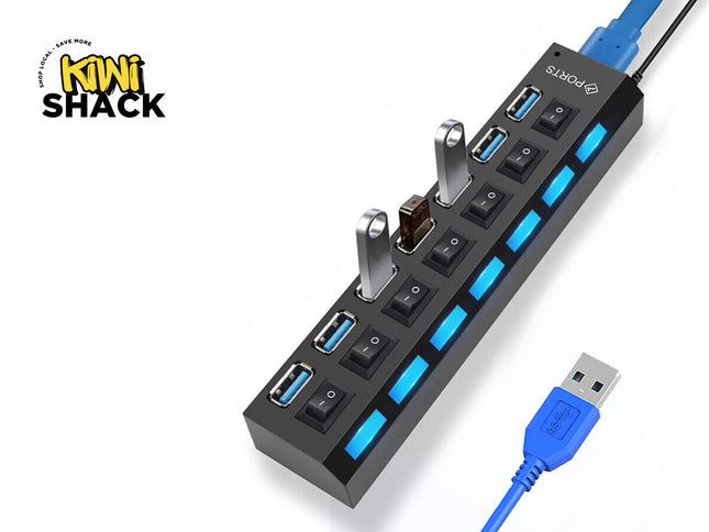 A black multi-port USB hub with individual power switches and blue LED indicators, with two USB flash drives plugged into it and a blue USB cable extending outward, set against a white background with the "Kiwi Shack" logo in the top left corner.