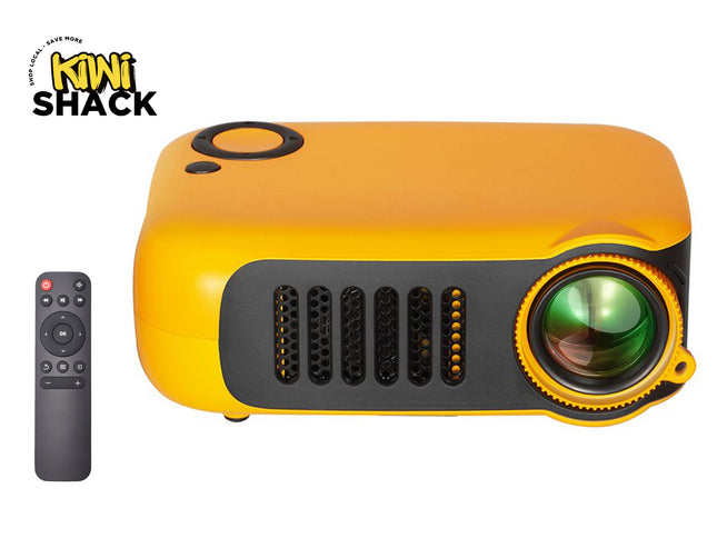 A bright yellow and black mini projector with a prominent side lens and ventilation grilles on the front, accompanied by a small gray remote control placed to the left, featuring a "Kiwi Shack" logo in the top left corner.