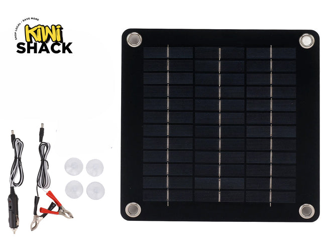 A square solar panel kit with four corner mounting grommets, accompanied by a cigarette lighter adapter cable, battery alligator clips, and four suction cups, with a "Kiwi Shack" logo in the top left corner.