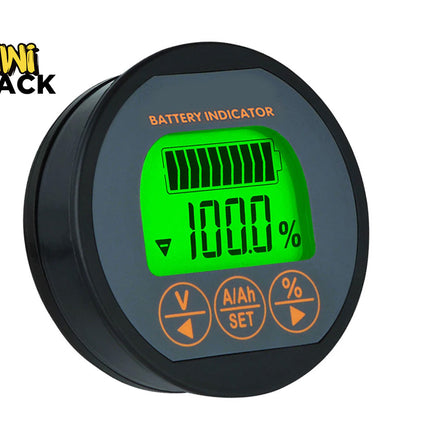 A round black battery indicator display unit with a green backlit LCD screen showing 100% battery level and orange buttons below, on a white background with a Kiwi Shack logo in the top-left corner.