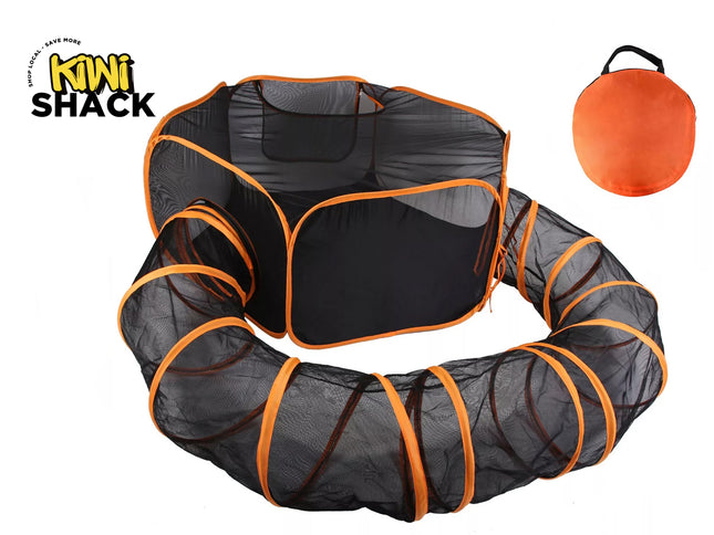 Black mesh play tunnel with bright orange trim, shown partially unfolded on a white background, with a small orange carrying bag in the upper right and the KiNi ShAcK logo in the upper left.