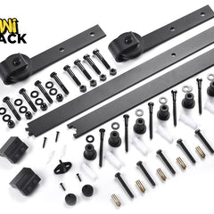 A black sliding barn door hardware kit including tracks, rollers, and mounting fasteners, featuring the "Kiwi Shack" logo in the top-left corner.
