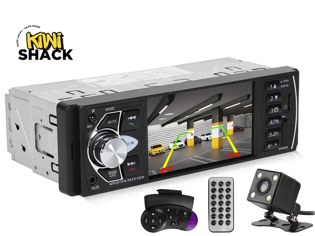 A Kiwi Shack car stereo headunit with a built-in rearview screen showing a parking garage image, accompanied by a remote control, a backup camera, and a handbrake switch on a white background.