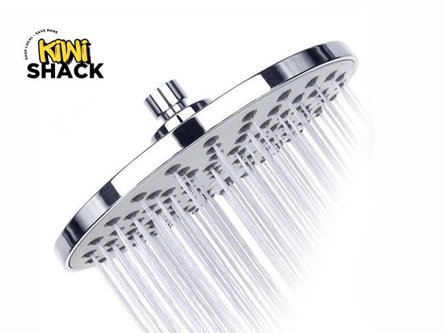 A chrome rainfall shower head with water actively spraying from its nozzle holes, featuring the "Kiwi Shack" logo in the top-left corner.