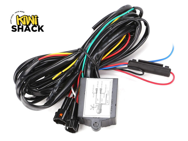 A black wiring harness with a central electronic control module, featuring multiple colored wires in red, yellow, green, and blue, and various connector plugs. The Kiwi Shack logo is visible in the top-left corner.