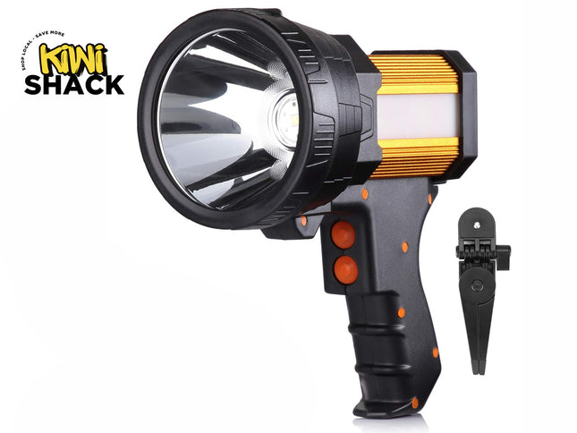 A black and gold high-intensity LED spotlight with a pistol-grip handle, orange control buttons, a side floodlight panel, and a small folding tripod stand on the right, set against a white background with the "Kiwi Shack" logo in the top left corner.