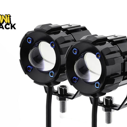 A pair of black round LED projector spotlight pods with U-shaped mounting brackets, threaded bolt bases, and blue accent screws, featuring a "Kiwi Shack" logo in the top left corner.