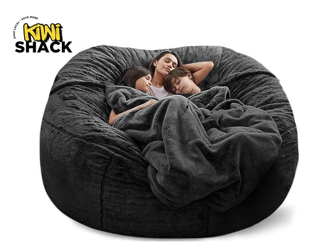 Large dark gray bean bag chair with a family of four wrapped in a blanket, branded 'Kiwi Shack'.