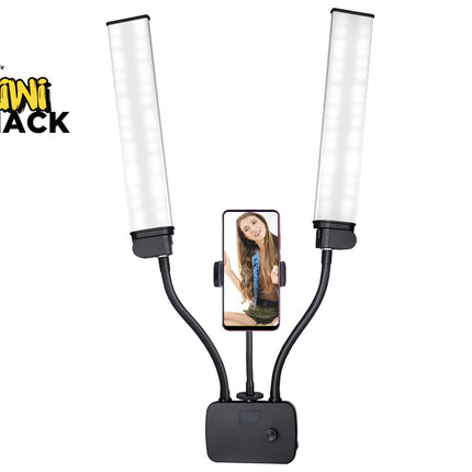 A dual LED light panel selfie stick by Kini Shack, featuring two adjustable flexible arms with bright white light tubes and a central black mounting base. A smartphone is shown in the center holder displaying a selfie video, set against a plain white background with the Kini Shack logo in the top-left corner.