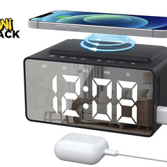 A black digital alarm clock radio with a mirrored display showing white time numbers, a top wireless charging pad holding a smartphone, a side-mounted USB charging cable, and a wired white charging case against a white background, featuring the "Kiwi Shack" logo in the upper left corner.