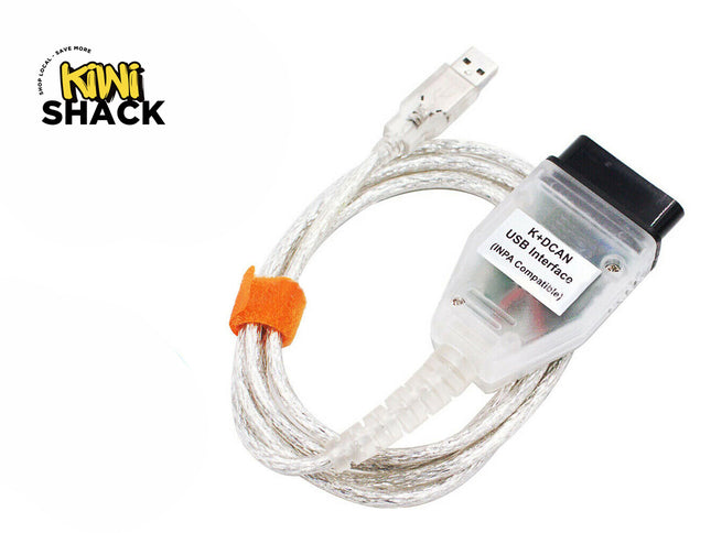 K+DCAN USB diagnostic interface cable (INPA compatible) with a transparent OBD2 diagnostic connector labeled "K+DCAN USB Interface (INPA Compatible)", a clear USB connector, coiled clear cable with an orange velcro cable tie, and the Kiwi Shack logo watermark.