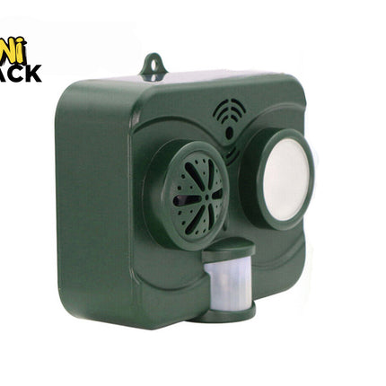 A dark green outdoor solar-powered animal repeller device featuring a motion sensor and speaker grille, with a "Kiwi Shack" logo in the top left corner.