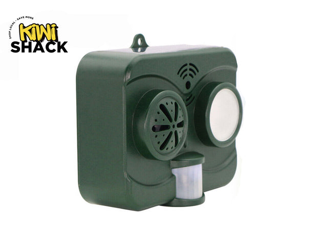 A dark green outdoor solar-powered animal repeller device featuring a motion sensor and speaker grille, with a "Kiwi Shack" logo in the top left corner.