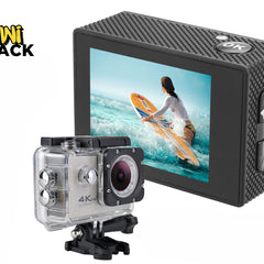 A 4K action camera shown both bare with its textured black housing and back display, and encased in a clear waterproof protective housing mounted on a base, with the screen displaying a surfer on a yellow board against a white background, featuring the "Kiwi Shack" logo in the upper left corner.