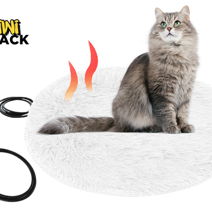 A round white fluffy heated pet bed occupied by a long-haired grey cat, shown alongside a USB power cable and a protective black cord cover against a white background, featuring the "Kiwi Shack" logo in the upper left corner.