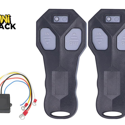 Two black wireless winch remote controls with grey "IN" and "OUT" directional buttons, shown with a matching black receiver module with multi-colored wiring harnesses and ring terminals on the bottom left, featuring Kiwi Shack logo in top left.