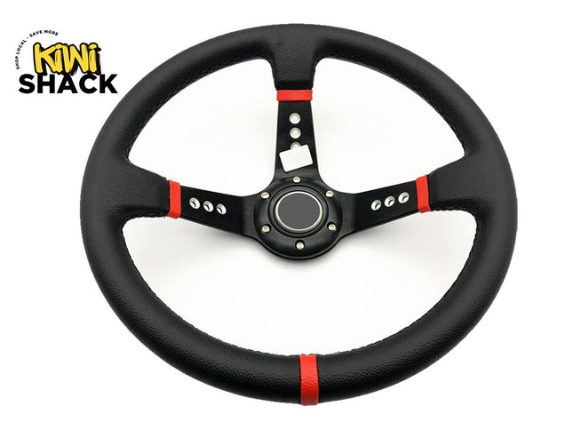 A black leather steering wheel with red accent stripes and a black center cap, shown on a white background with the Kiwi Shack logo in the top-left corner.