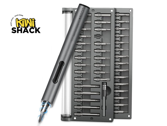A Kiwi Shack electric screwdriver with a dark gray metallic body, shown alongside its storage tray and a clear cylindrical battery case on a white background. The Kiwi Shack logo is visible in the top-left corner.