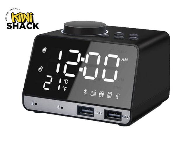 A modern black digital alarm clock radio with a large LED display showing the time and temperature, a top rotary volume dial, control buttons, and two front USB charging ports, featuring a "Kiwi Shack" logo in the top left corner.