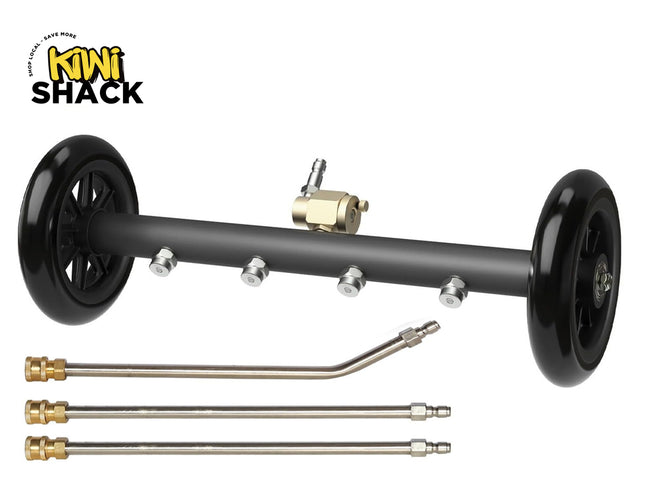 Product shot of a black undercarriage pressure washer attachment with two black wheels on either end, four stainless steel spray nozzles along the bar, a brass inlet valve with a quick-connect plug at the top center, and three extension wands placed underneath. The 'Kiwi Shack' logo appears in the top left corner.