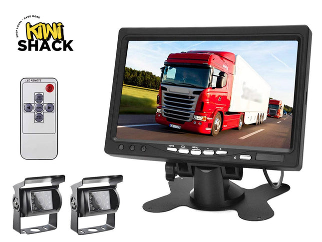 A backup camera and monitor kit featuring a large dashboard display showing a red semi-truck, a handheld remote control, and two rearview cameras with mounting brackets against a white background, with the "Kiwi Shack" logo in the upper left corner.