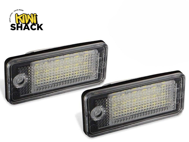 Two rectangular LED license plate lights with clear textured lenses and black housings, featuring the "Kiwi Shack" logo in the top-left corner.