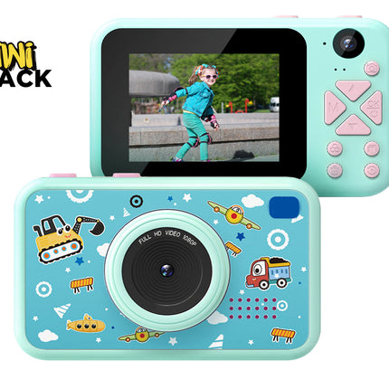 A children's digital camera in mint green and light blue with cartoon graphics, shown from both front and back angles on a white background, with the Kiwi Shack logo in the top left corner.
