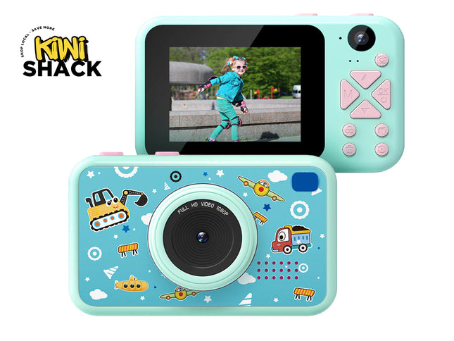 A children's digital camera in mint green and light blue with cartoon graphics, shown from both front and back angles on a white background, with the Kiwi Shack logo in the top left corner.
