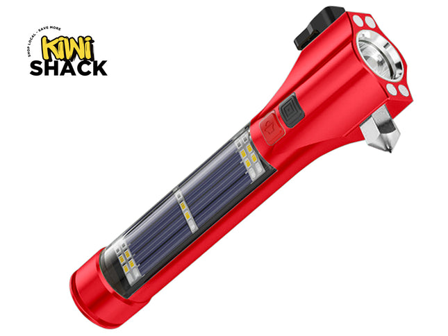 A red multi-function emergency safety flashlight featuring a built-in solar panel, side utility LEDs, a glass breaker hammer tip, and control buttons against a white background, featuring the "Kiwi Shack" logo in the upper left corner.